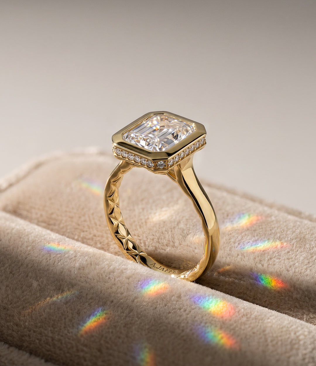 A gold ring with a large rectangular clear gemstone and small accent stones along the top, photographed close up on a soft beige surface.